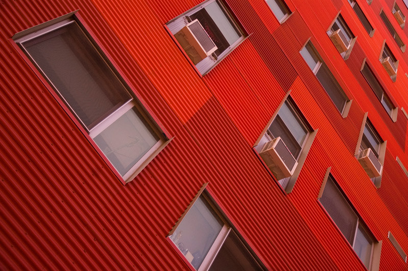 A red building with air conditioners in the windows.