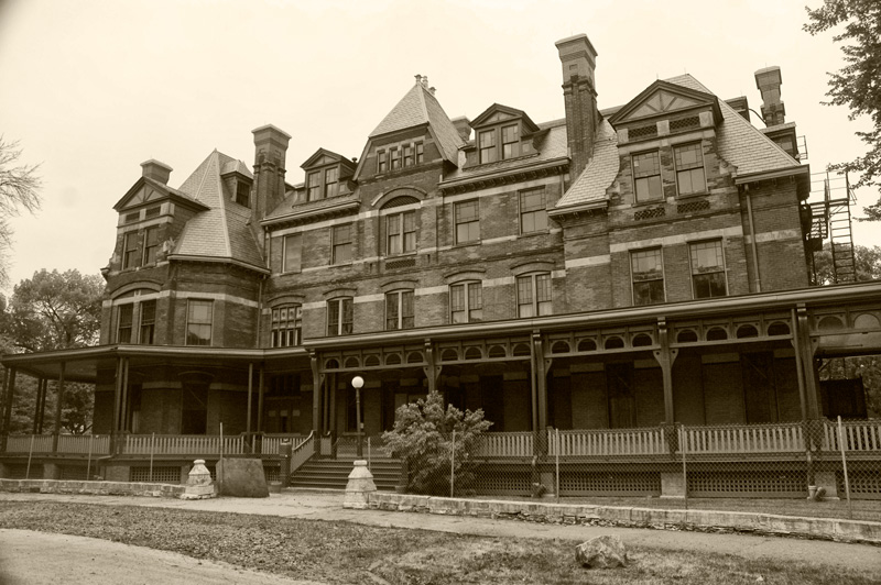 A large Victorian building with a surrounding porch.