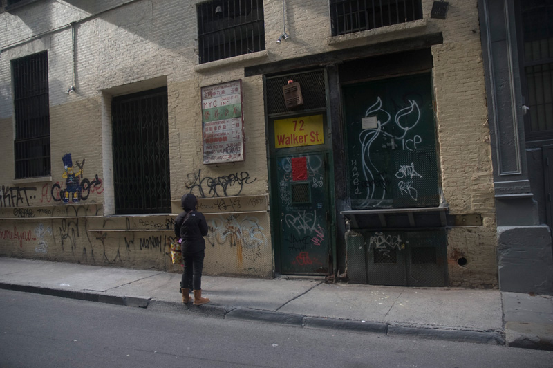 A child looking at a door in an alley.