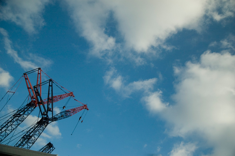 Two building cranes in a blue sky.