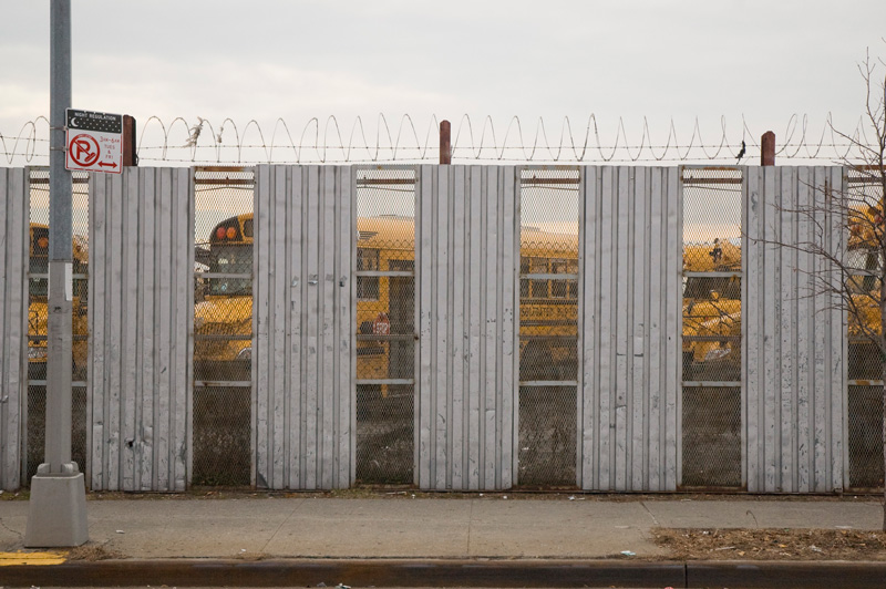 School buses, parked behind a fence.