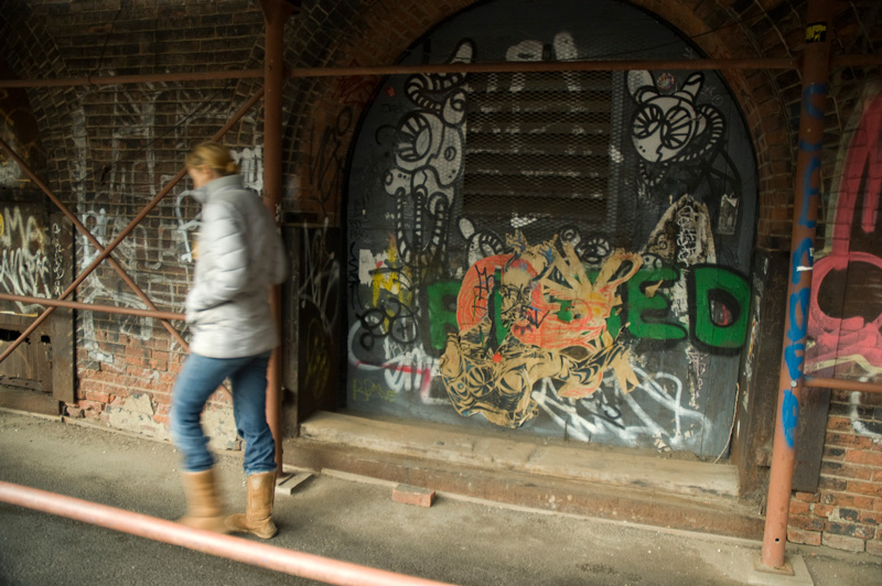 A woman walks past graffiti.