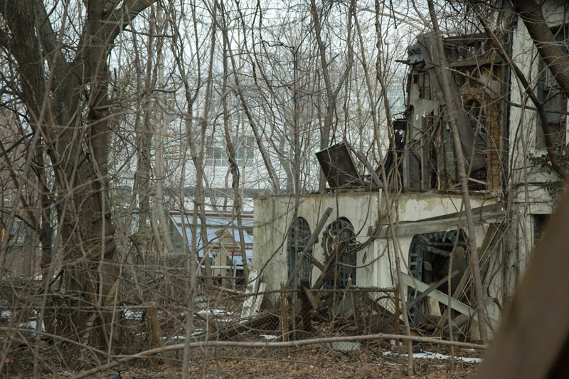 A building in ruins, amid barren trees.