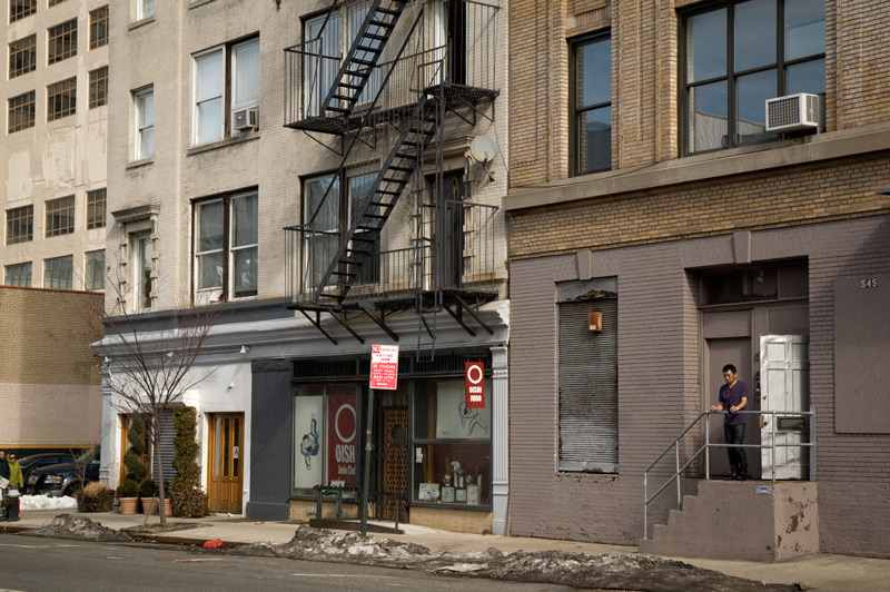 Storefronts, and a man on a stoop.