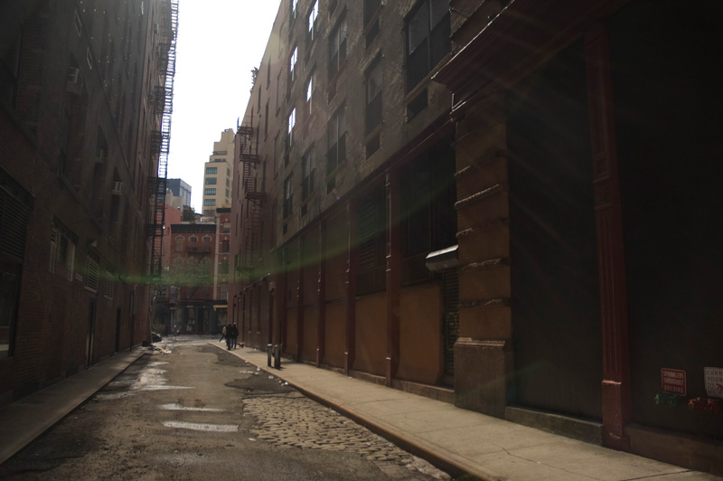 Sun shining into a street with cobblestones.