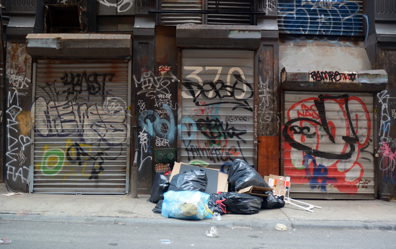 Trash bags on an alley sidewalk.