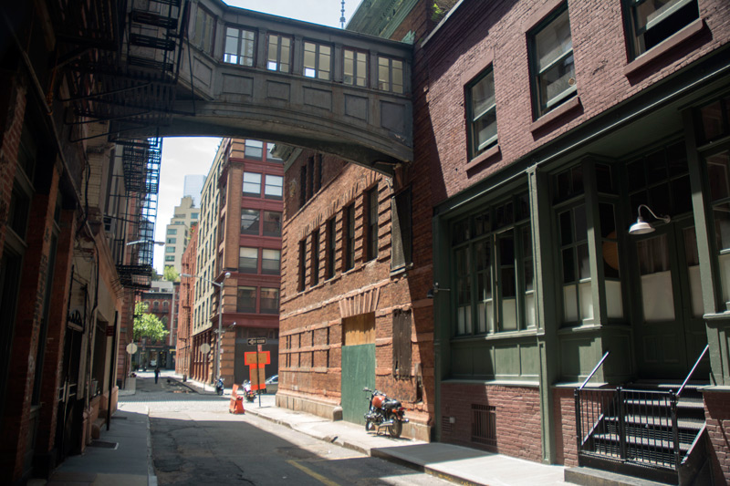 A thin street, with a pedestrian bridge.