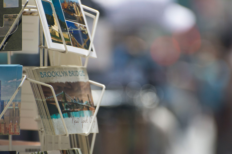 A picture postcard of the Brooklyn Bridge, on a sales rack.