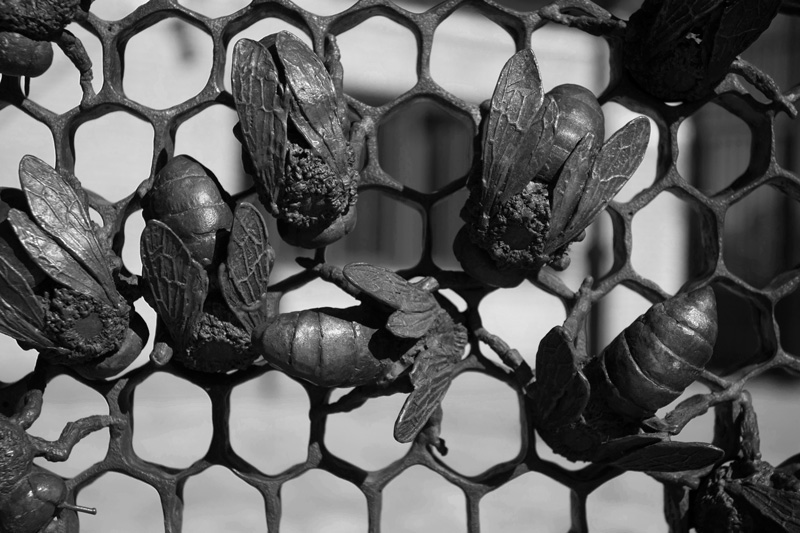 Metal bees on a honeycomb fence
