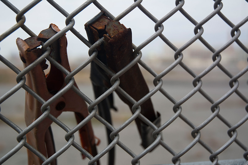 Rusted battery clamps on a chain link fence