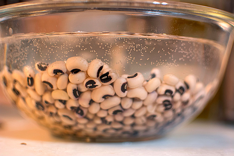 Black-eyed peas soaking in a glass bowl.