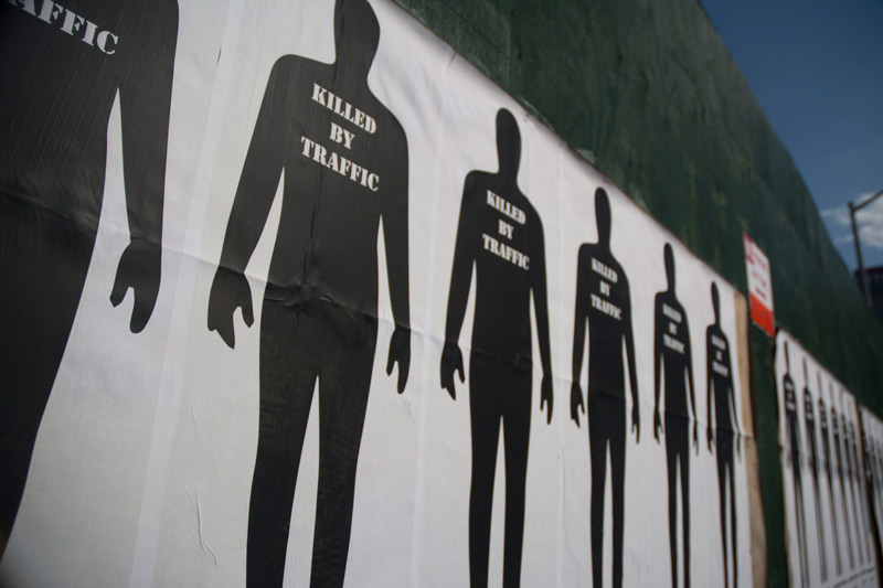 Silhouette figures on a fence, stencilled 'Killed by Traffic.'