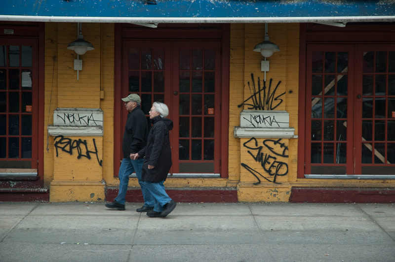 People pass an abandoned restaurant tagged with 'Wemkia.'