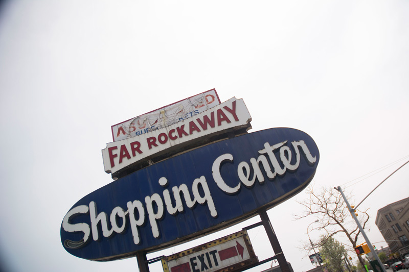 A beaten-up, aged sign for a shopping center