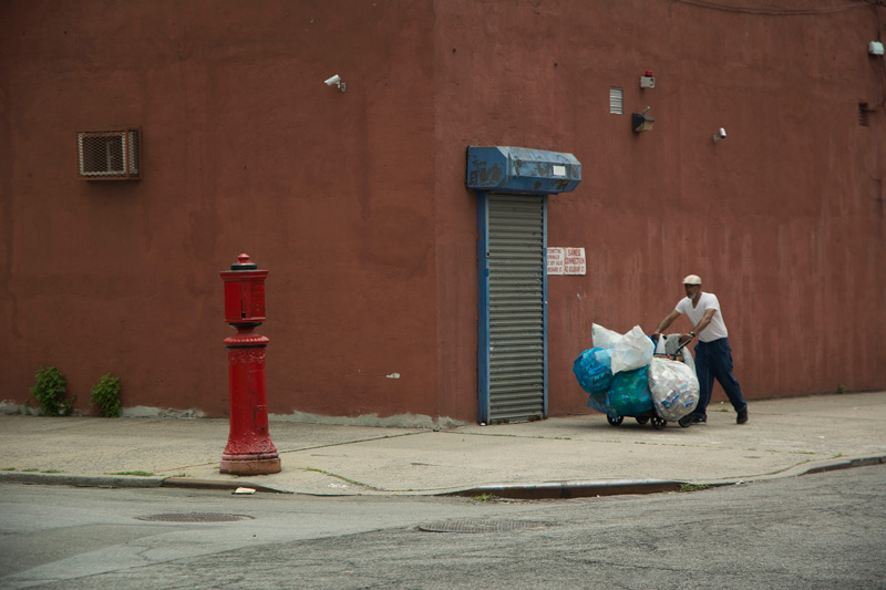 A man pushing a cart with bags full of deposit cans and bottles