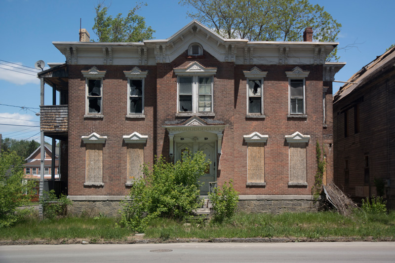 A once grand home, boarded up and in decay,