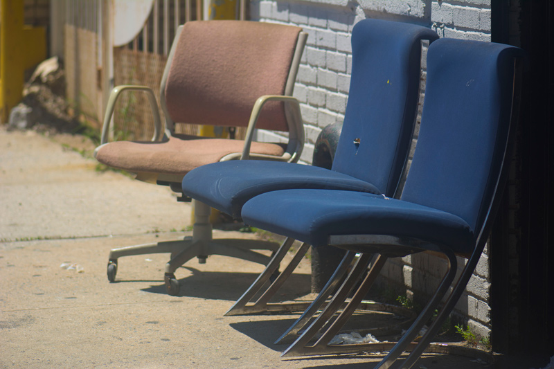 Three discarded office chairs awaiting the trash.