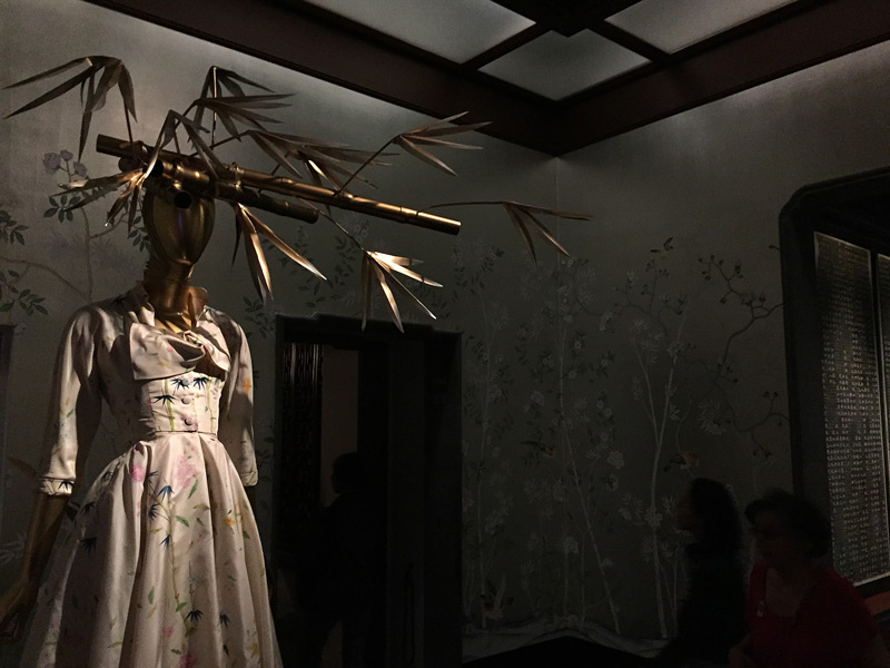 A mannequin in Chinese garb has bambooo stalks on her head.