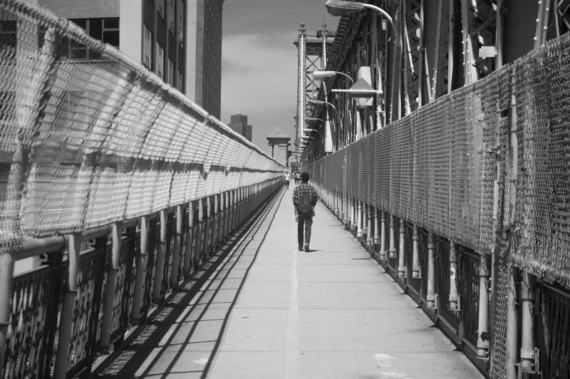 A person walking acrosss the Manhattan Bridge.