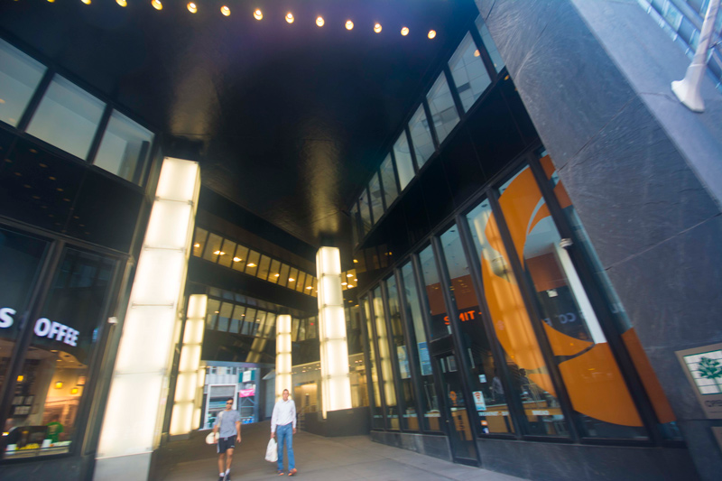 Two people walk past stores in a passageway.