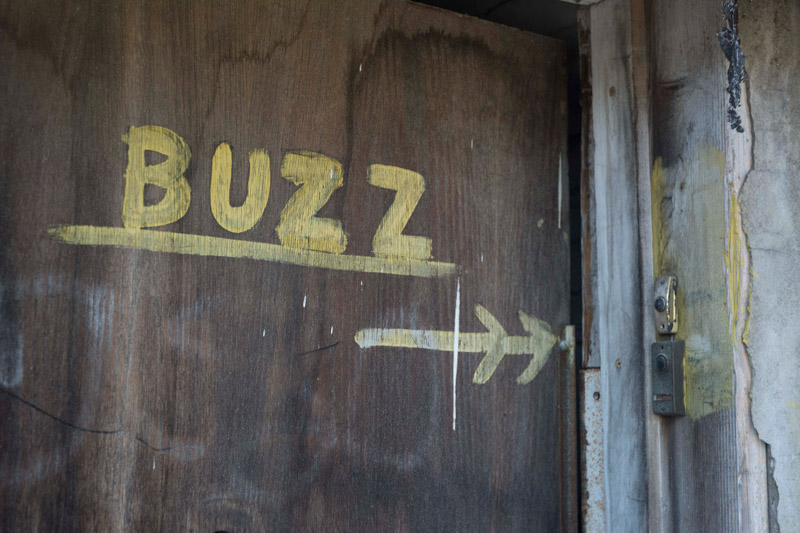 The word 'Buzz' on a door, painting to a buzzer.