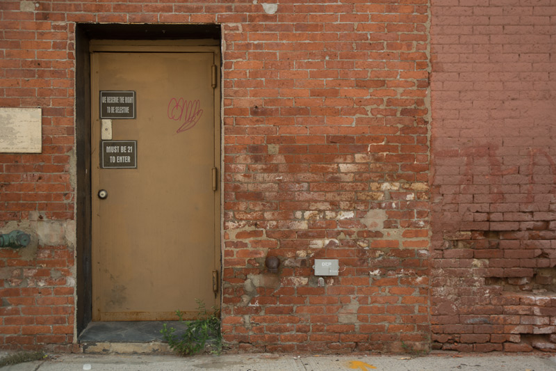 A forbidding door to a lounge, in a brick building