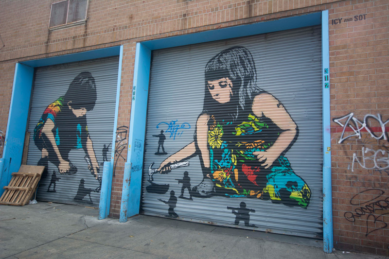 Street art, showing two children taking hammers to war toys.