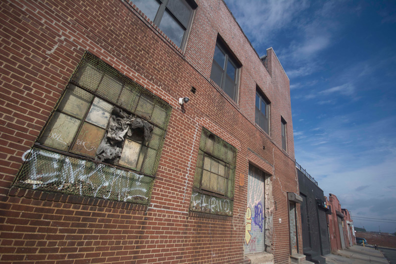 An industrial building has blue skies above it, streaked with clouds.