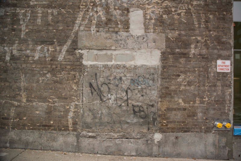 An aged brick wall, with cracks and graffiti.