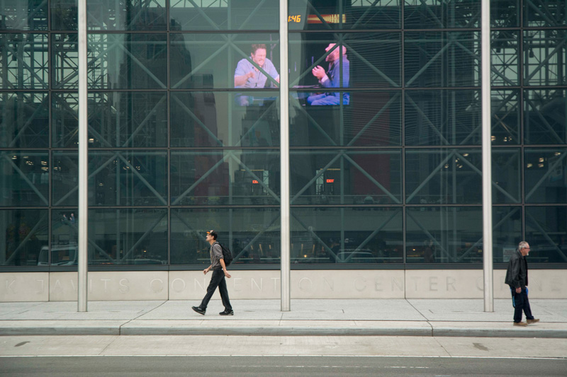 Men walking past the glass walls of the Jacob Javit Convention Center.