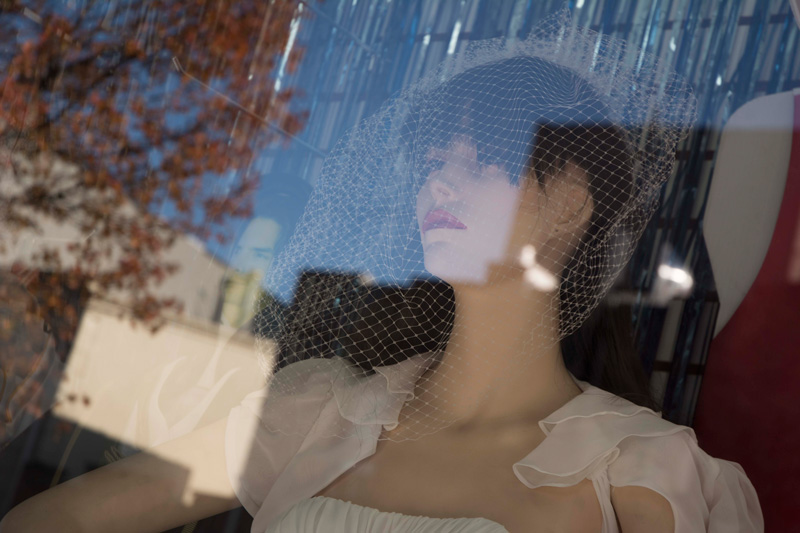 A mannequin in a store window, in bridal dress.