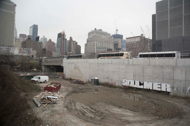 A construction site, with pooled water and graffiti on a wall.