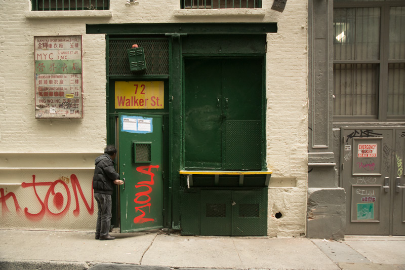 A man walking into a brick building.