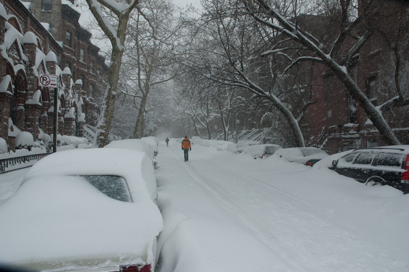 A man walking down the road on a snowy street.