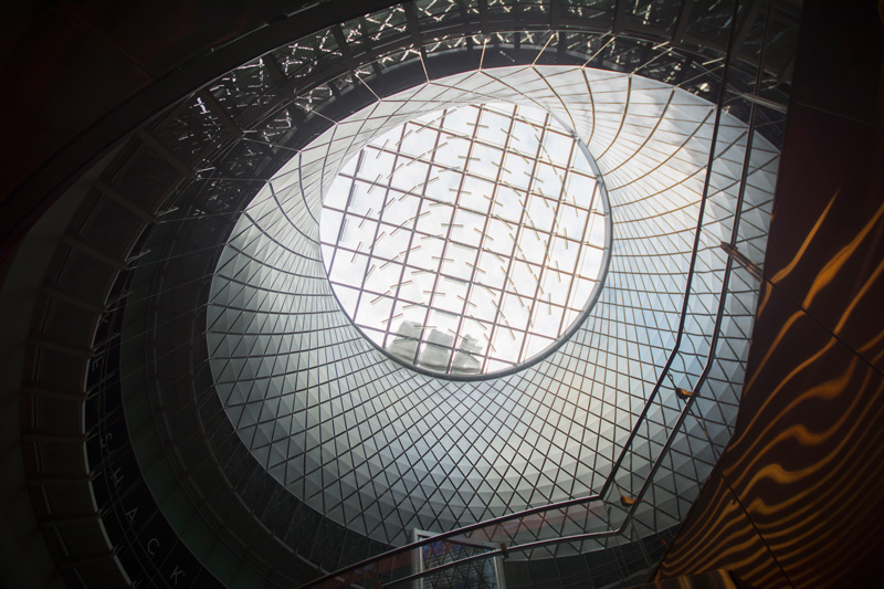 Sunlight streams through an oculus in a metal room.