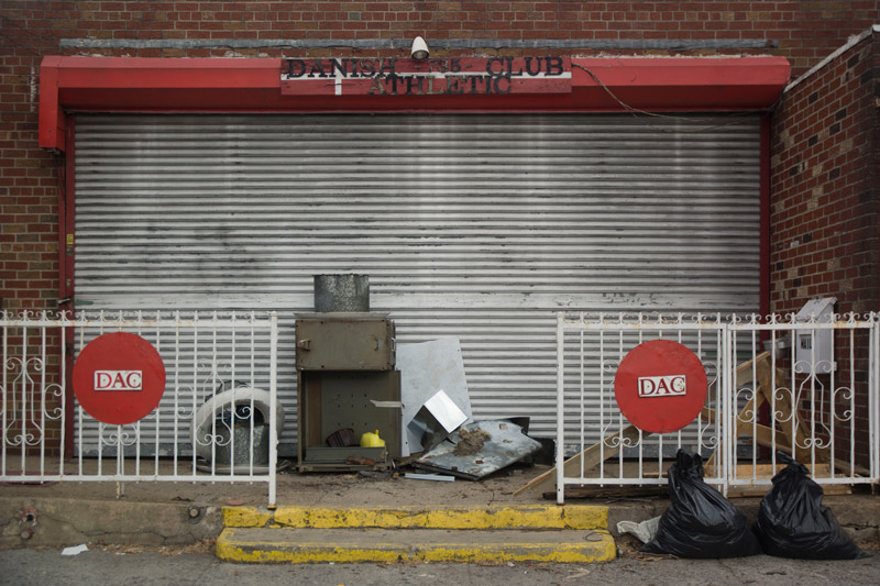 Signage at a building front saying the 'Danish Athletic Club,' but debris suggests they're gone.