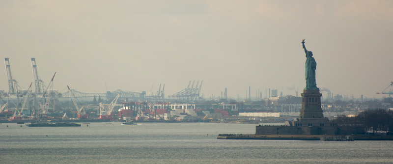 The Statue of Liberty, shipping cranes, and bridges of New York Harbor.