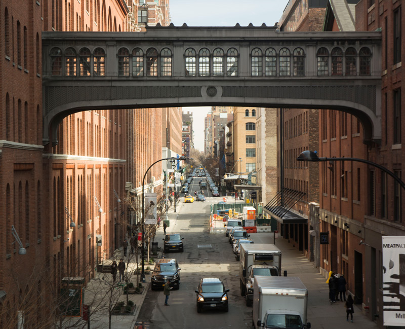 A pedestrian bridge between two buildings, with a veiw in the distance of many blocks.