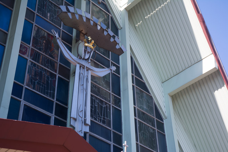 A statue of Jesus above a church entrance, with arms spread and welcoming.