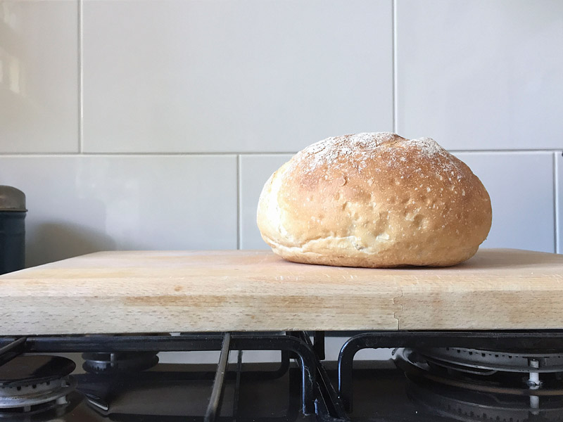 An unsliced loaf of bread, sitting on a cutting board.
