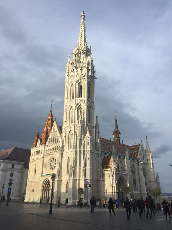 The steeple of King Matthias Church in Budapest rising to the sky.