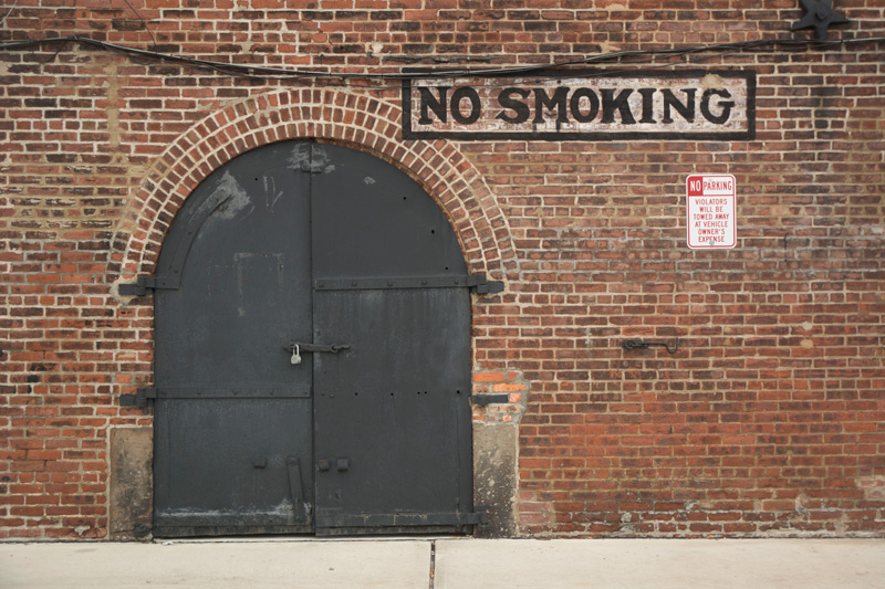 A 'No Smoking' sign, artistically painted on a brick wall.