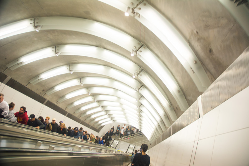 A long line of people ascending on an escalator.