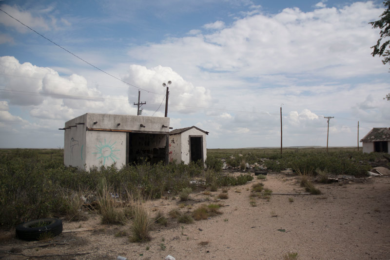 A one-story, abandoned building in the desert scrub.