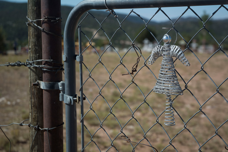 A small, metal angel adorns a chain-link gate to a cemetery.