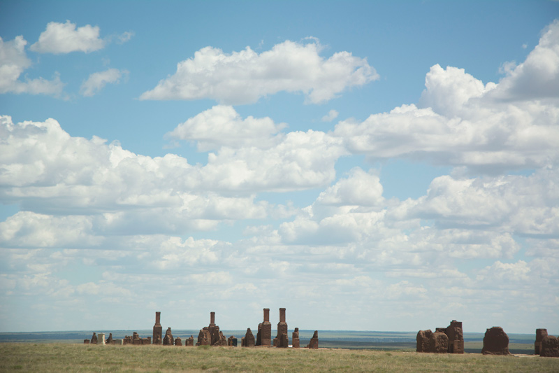 The ruins of chimneys and worn walls on the prairie.