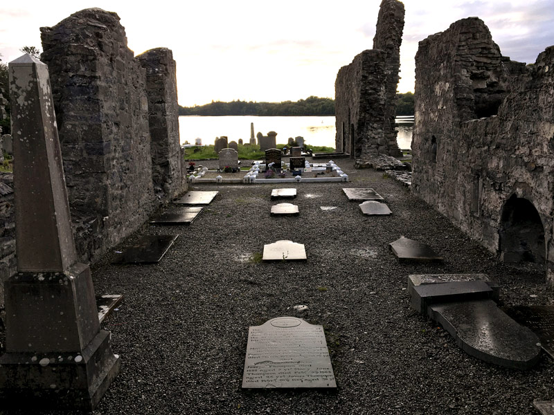 The ruins of an abbey, with gravestones within.