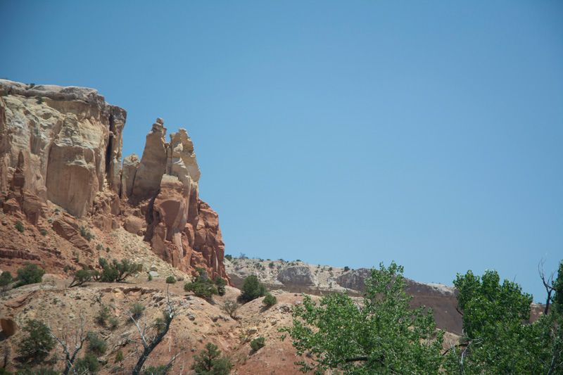 A mesa, with a variety of colored layers, stands out against a blue sky.