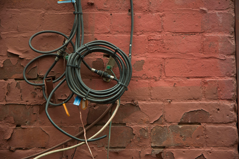Coaxial cable, wrapped in a tight coil and fastened to a red brick wall.