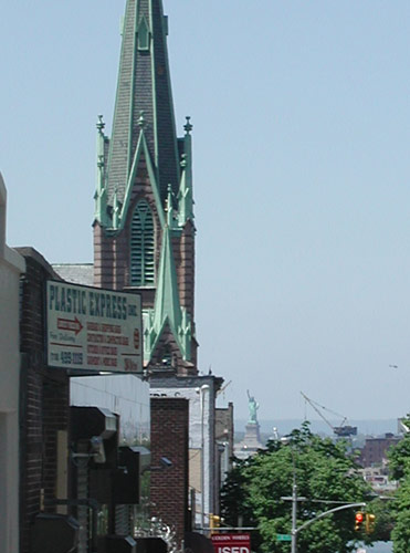 A church
steeple on the left, with the Statue of Liberty far in the
background.